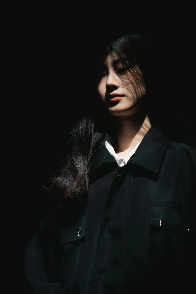 A woman in a black jacket in shadow