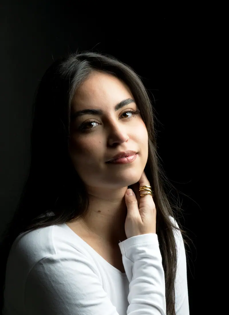 A smiling woman with long hair against a dark backdrop