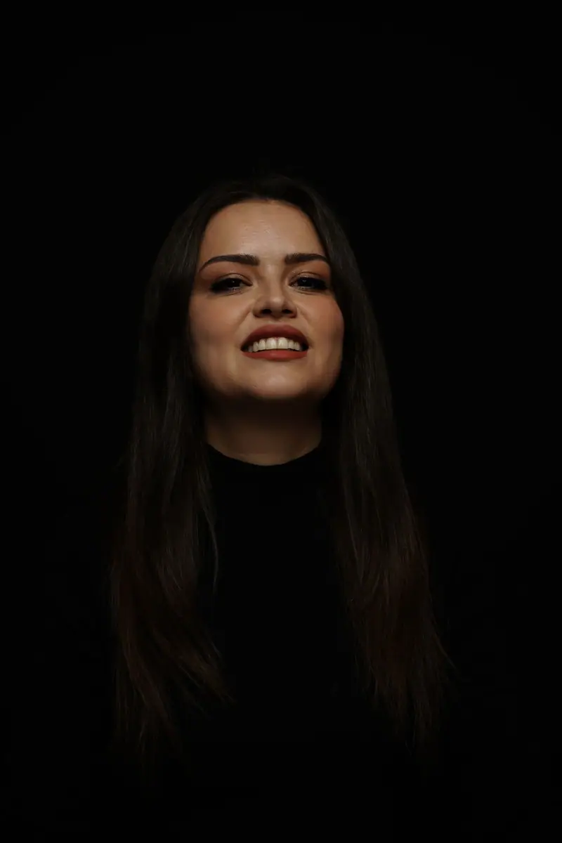 A smiling woman with long dark hair against a dark backdrop
